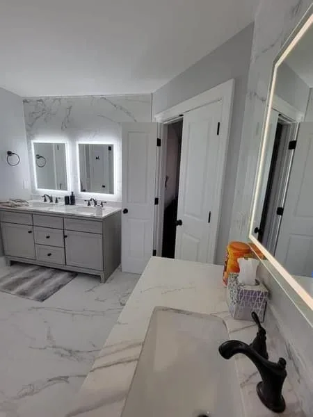 Completed bathroom with grey double vanity and lit mirrors