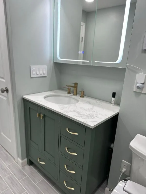 Completed bathroom vanity in green cabinetry with brass tapware