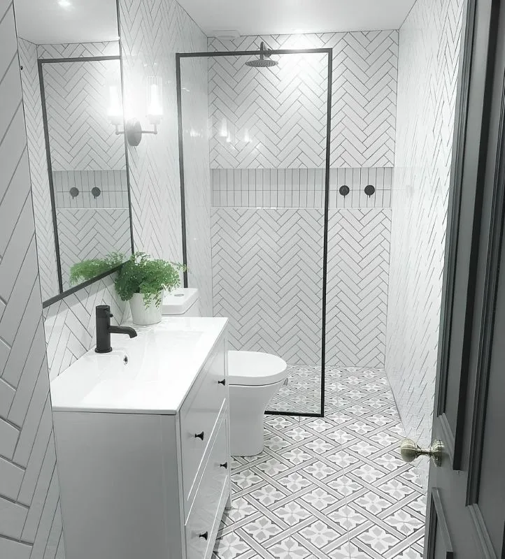 Completed shower with white herringbone tile and glass screen